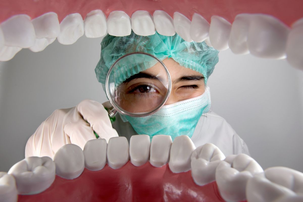 Dentista observando con lupa una boca - Clínica Mayor 4