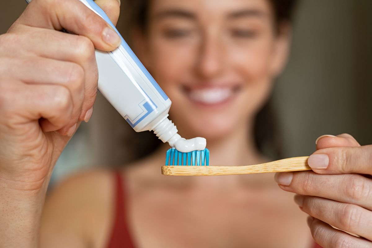 Mujer echando pasta dentífrica sobre su cepillo de dientes
