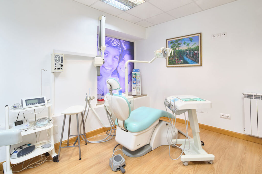Sala de atención a pacientes repleta de artilugios de odontología especializados y asiento de color azul celeste